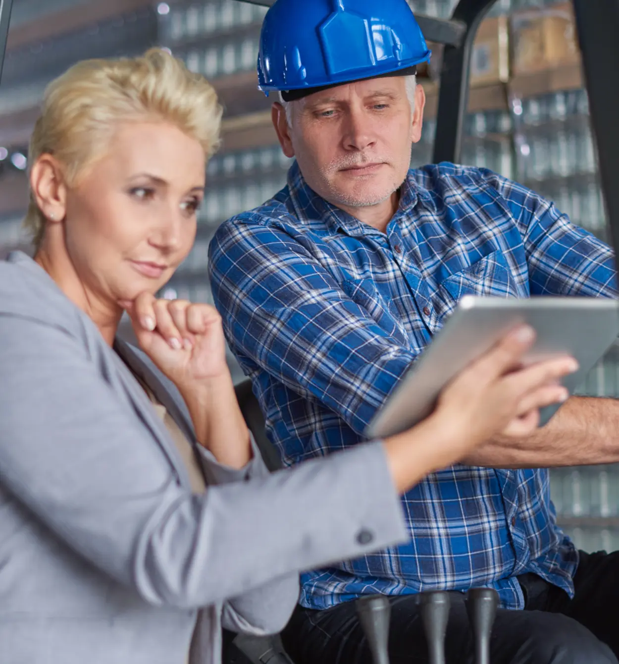 Two colleagues reviewing inventory on a tablet inside a warehouse